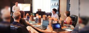 A team in an office discussing email newsletter software during a meeting