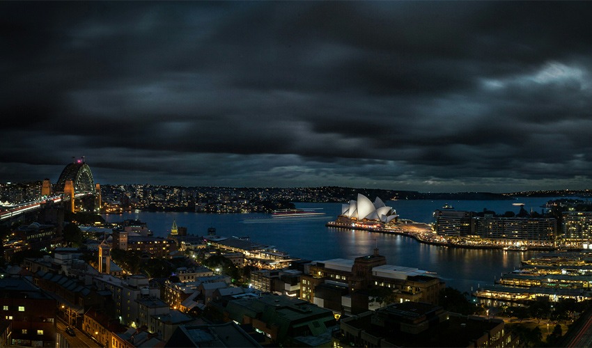 aerial shot of Sydney Harbour with the Sydney Opera House and Sydney Harbour Bridge lit up in the background
