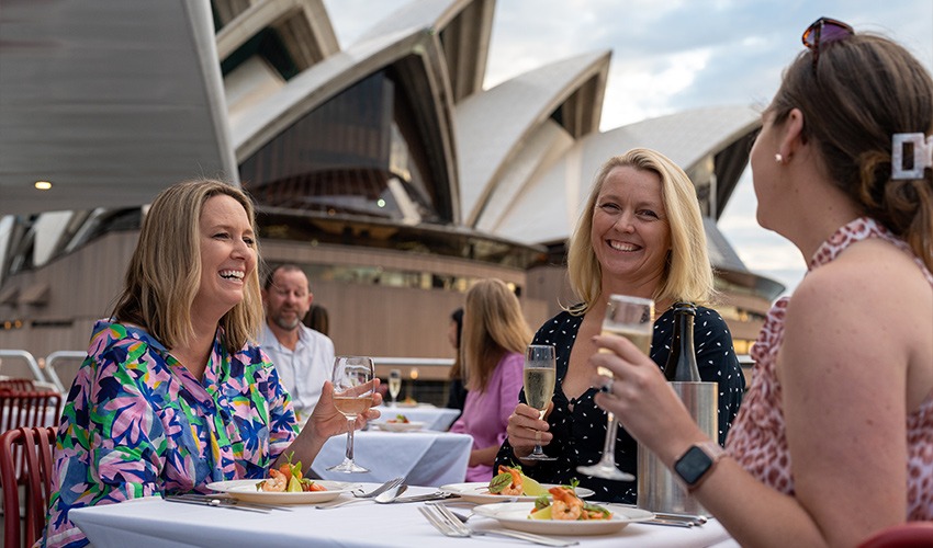Women toasting champagne on a Sydney Harbour lunch cruise with the Opera House in view